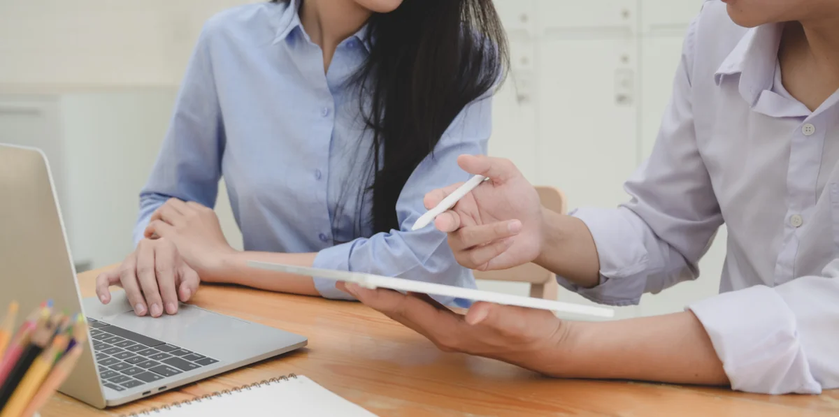 Colleagues reviewing information on a tablet beside a laptop